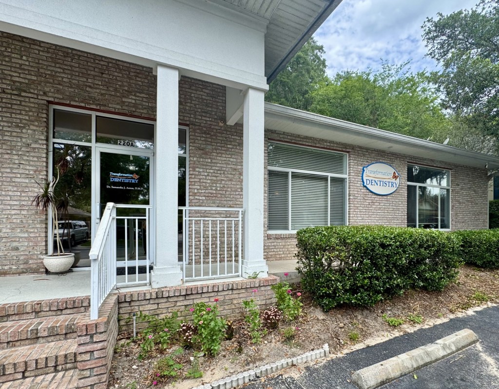 Front entrance of brick dental office with white columns and signage