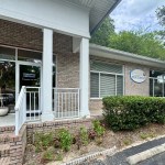 Front entrance of brick dental office with white columns and signage